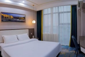 Une chambre d’hôtel avec un grand lit, un tableau au mur, une fenêtre avec des rideaux et un bureau avec une chaise.