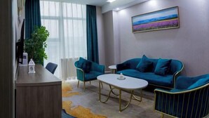 Une chambre d’hôtel moderne, équipée d’un canapé, d’une petite table, d’un radiateur et d’une grande fenêtre avec des rideaux.