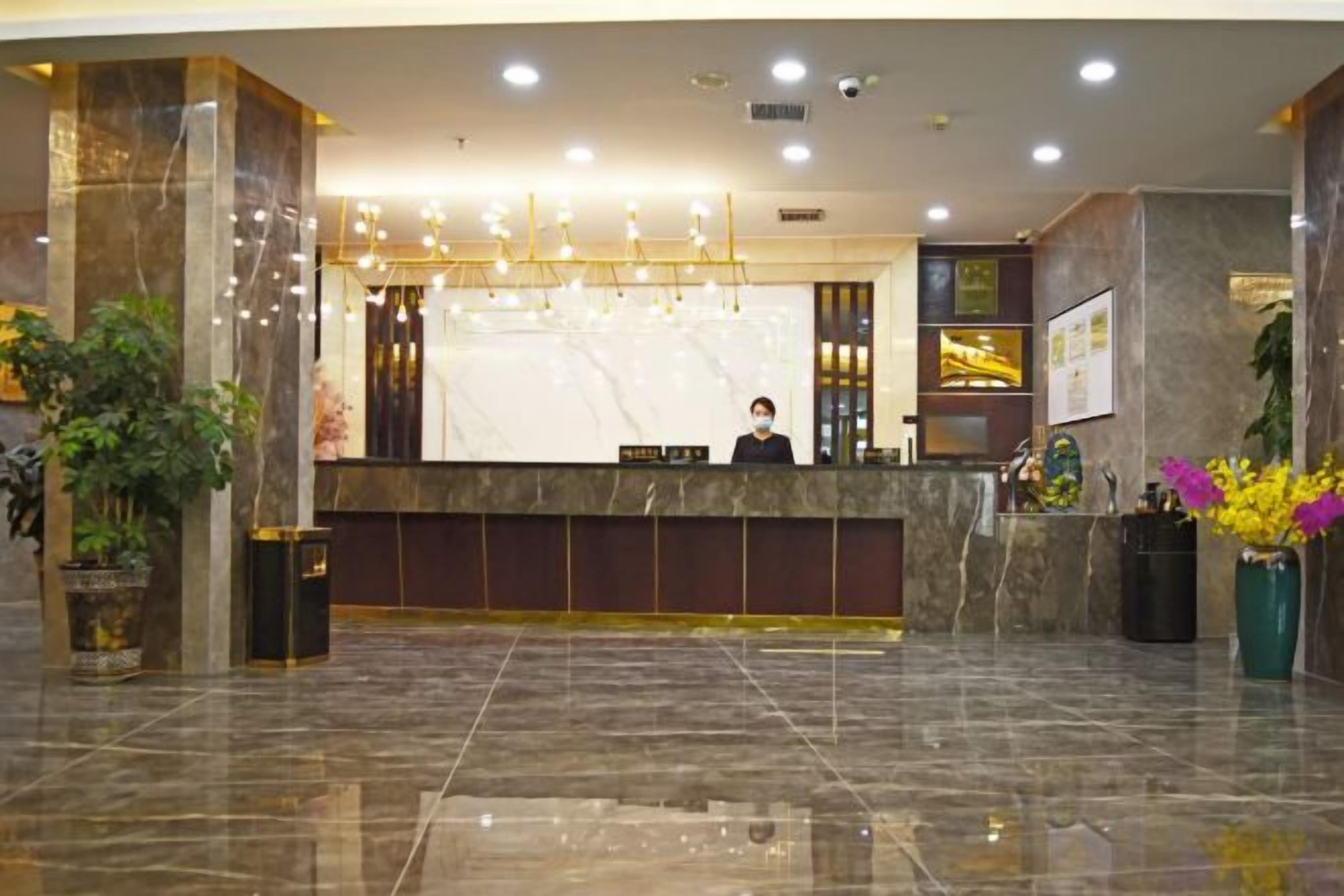 A hotel reception area with a marble counter, a receptionist, and a large screen.