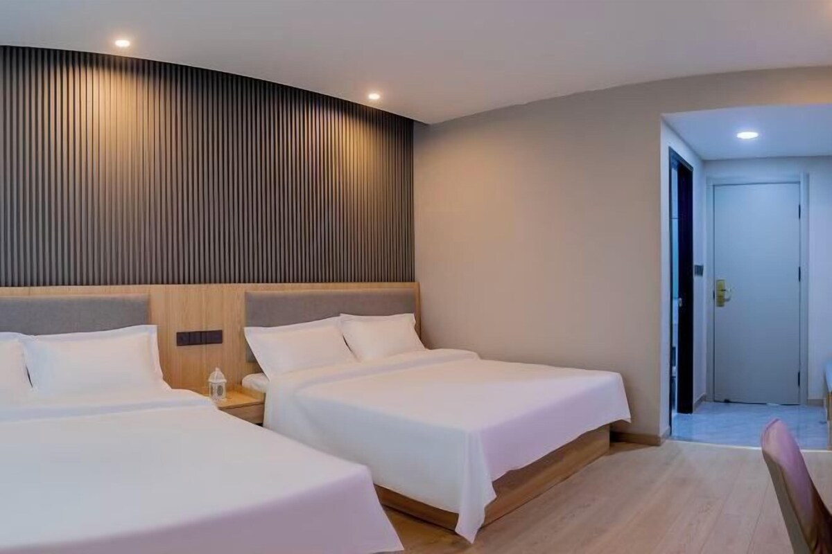 A hotel room with two beds, a wooden headboard, and a curved wall with vertical lines.