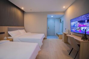 A hotel room with two beds, a desk, a TV, and a door leading to a bathroom. - Dushanzi Hotel (Karamay)
