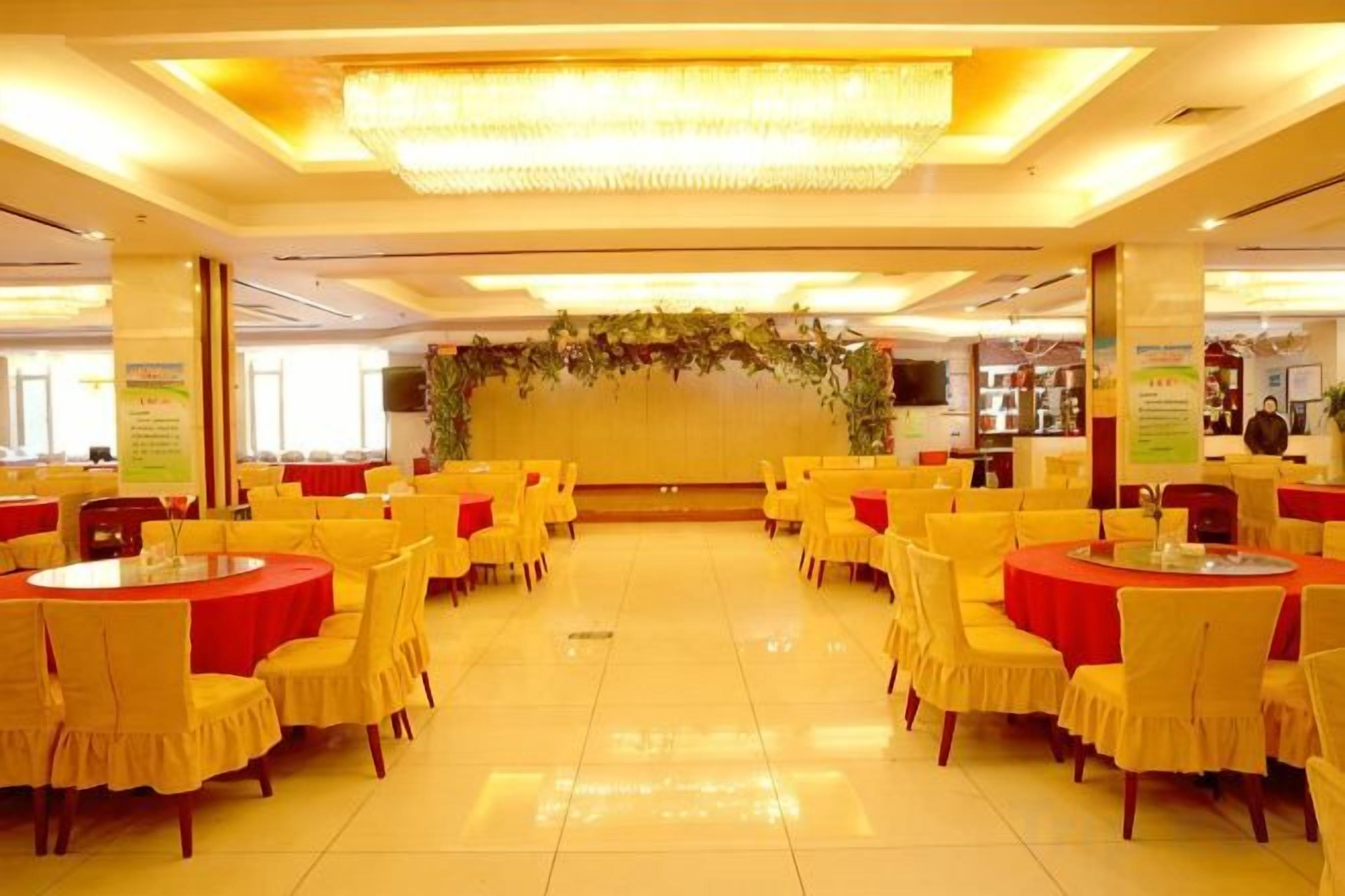 Un salón de banquetes con mesas redondas y sillas, un arreglo floral en el centro y piso de baldosas.