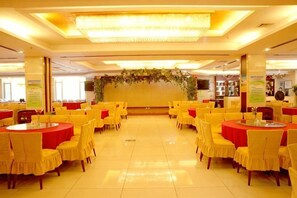 A banquet hall with round tables and chairs, a central floral arrangement, and a tiled floor. - Dushanzi Hotel (Karamay)
