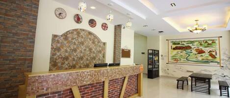 A reception area with a brick counter, a chandelier, and a large painting on the wall.