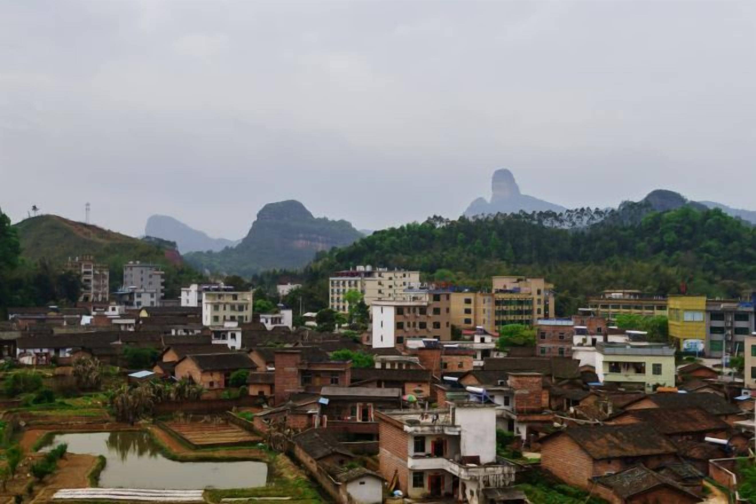 A town with traditional buildings and a prominent hill in the background.