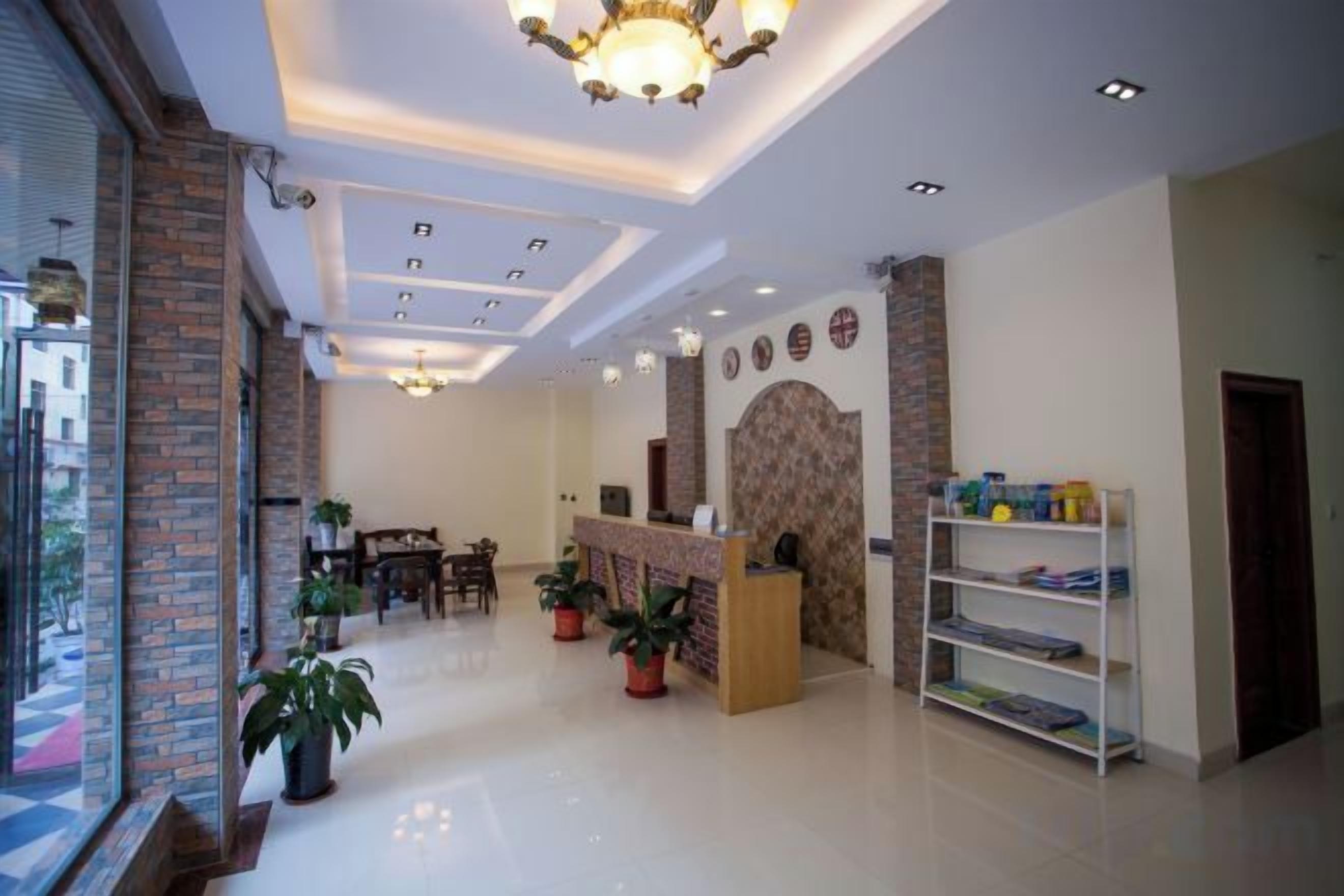 A hotel lobby with a reception desk, seating area, and potted plants.