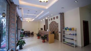 A hotel lobby with a reception desk, seating area, and potted plants.