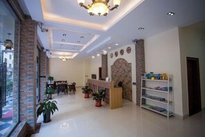 Un hall d’hôtel comprenant un comptoir d’accueil, un espace salon et des plantes en pot.