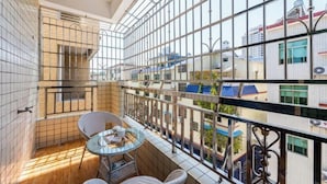 A balcony with a glass table and chairs, metal railings, and a view of neighboring buildings. - The story of Danxia Inn (Renhua)