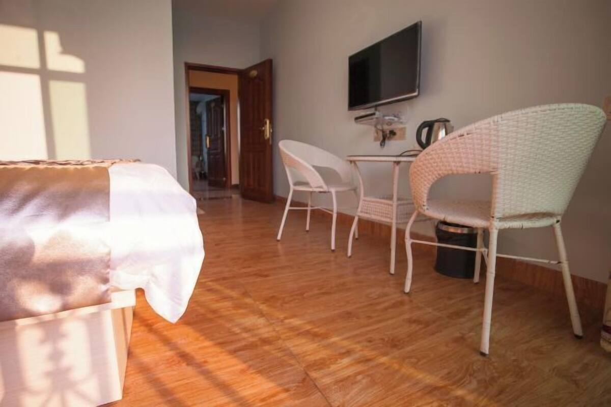 Een kamer met een bed, een televisie, een tafel en twee stoelen.