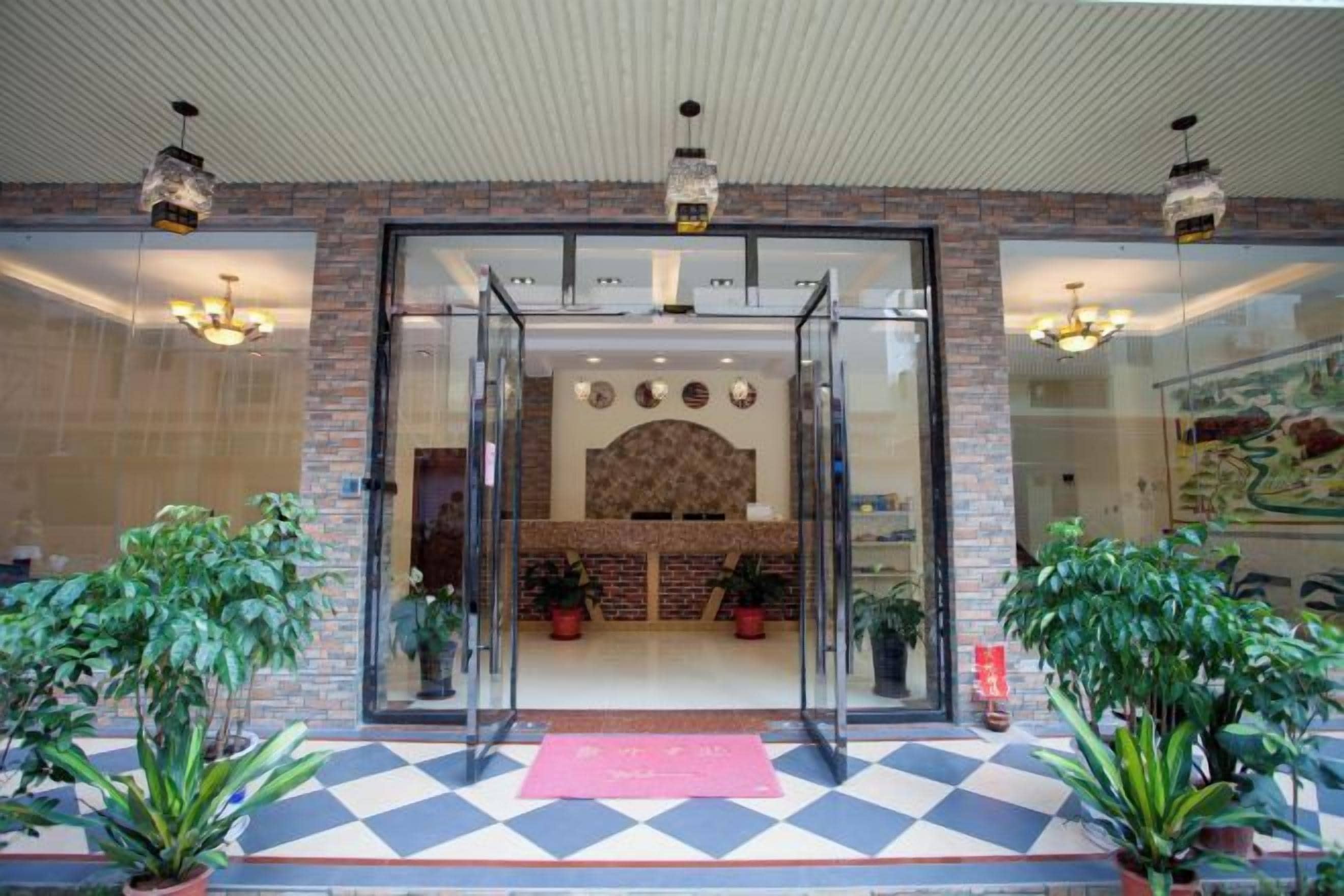 A hotel entrance with a check-in desk, potted plants, and a check-in area.