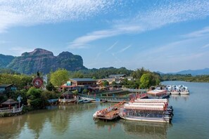 A riverside town with boats docked, a bridge, and buildings along the water. - The story of Danxia Inn (Renhua)