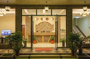 A lobby with a checkered floor, a reception desk, a fireplace, and potted plants.