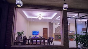 A dining area with a large table, chairs, and potted plants. - The story of Danxia Inn (Renhua)