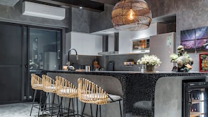 A modern kitchen with a central island, bar stools, and a built-in refrigerator. - Rolling Hills (Puli)