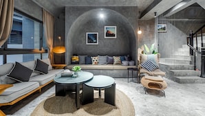 A modern living room with a sofa, coffee table, and a staircase. - Rolling Hills (Puli)