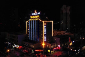 A multi-story building with illuminated signage, a prominent entrance, and a parking area.