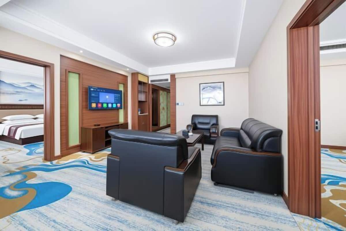 A hotel room with a bed, a TV, a sofa, and a massage chair.