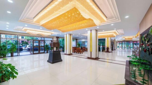 Een ruime lobby met een hoge plafond, grote ramen en een centraal zitgedeelte.