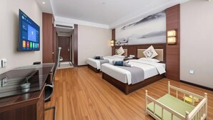 Een hotelkamer met een bureau, twee bedden, een televisie en een schilderij aan de muur.
