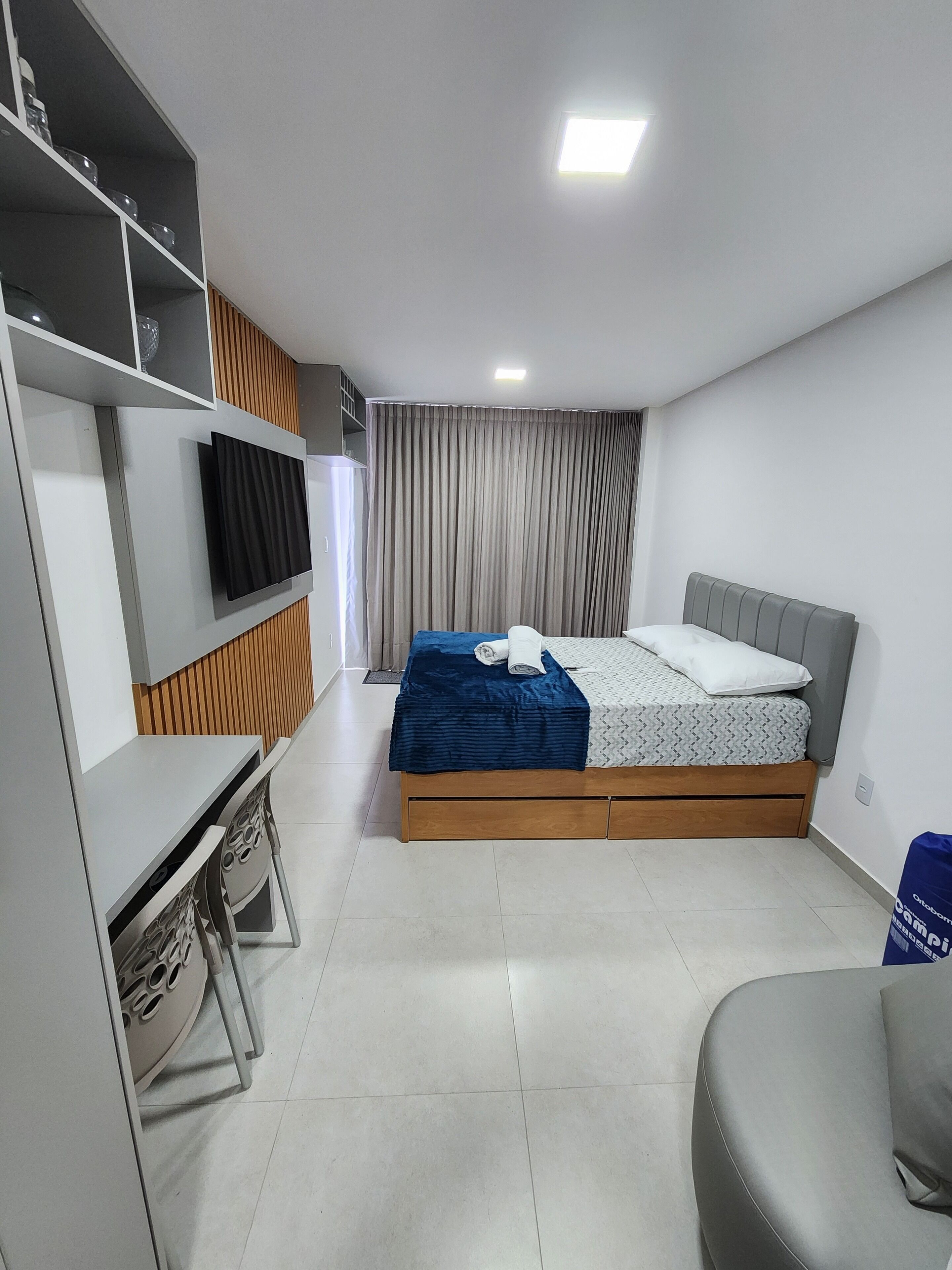 Une chambre à coucher moderne avec un lit, un bureau et un téléviseur.