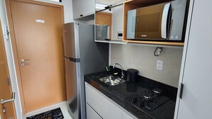 A modern kitchen with a refrigerator, stove, and microwave. - Flat Ofurô 02 VP by La Playa (Ipojuca)