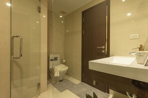 A modern bathroom with a glass shower enclosure, a toilet, and a sink with a marble countertop. - Beach Nicest Apartment In The title c123 (Rawai)
