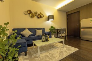 A modern living room with a blue sofa, a white coffee table, and decorative wall art. - Beach Nicest Apartment In The title c123 (Rawai)