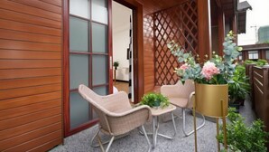 A wooden balcony with two wicker chairs, a small table, and a potted plant. - Beihai Yuhai Elegant Restaurant Hotel (Beihai International Passenger Transport Terminal) (Beihai)