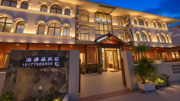 A multi-story hotel with a stone facade, arched windows, and a well-lit entrance. - Beihai Yuhai Elegant Restaurant Hotel (Beihai International Passenger Transport Terminal) (Beihai)