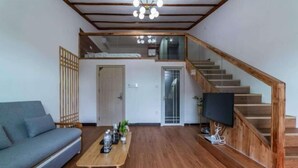 A modern living room with a sofa, coffee table, and a staircase leading to an upper level. - Beihai Yuhai Elegant Restaurant Hotel (Beihai International Passenger Transport Terminal) (Beihai)
