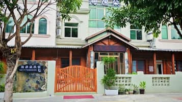 A building with a gated entrance, a signboard, and a potted plant.