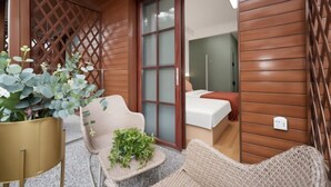 A wooden exterior wall, a sliding glass door leading to a room, and a wicker chair with a plant. - Beihai Yuhai Elegant Restaurant Hotel (Beihai International Passenger Transport Terminal) (Beihai)