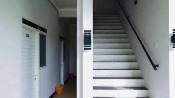A staircase with a handrail, a white door, and a window on the left wall.