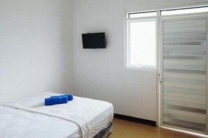 Ein Zimmer mit einem Bett, einem an der Wand befestigten Fernseher und einer Schiebetür.