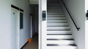 A hallway with a white door and a staircase with black handrails. - RedDoorz Syariah near RSUD Mataram Lombok 2 (Mataram)