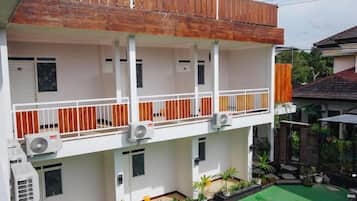 Un edificio a più piani con balconi, condizionatori d'aria e un'area verde.