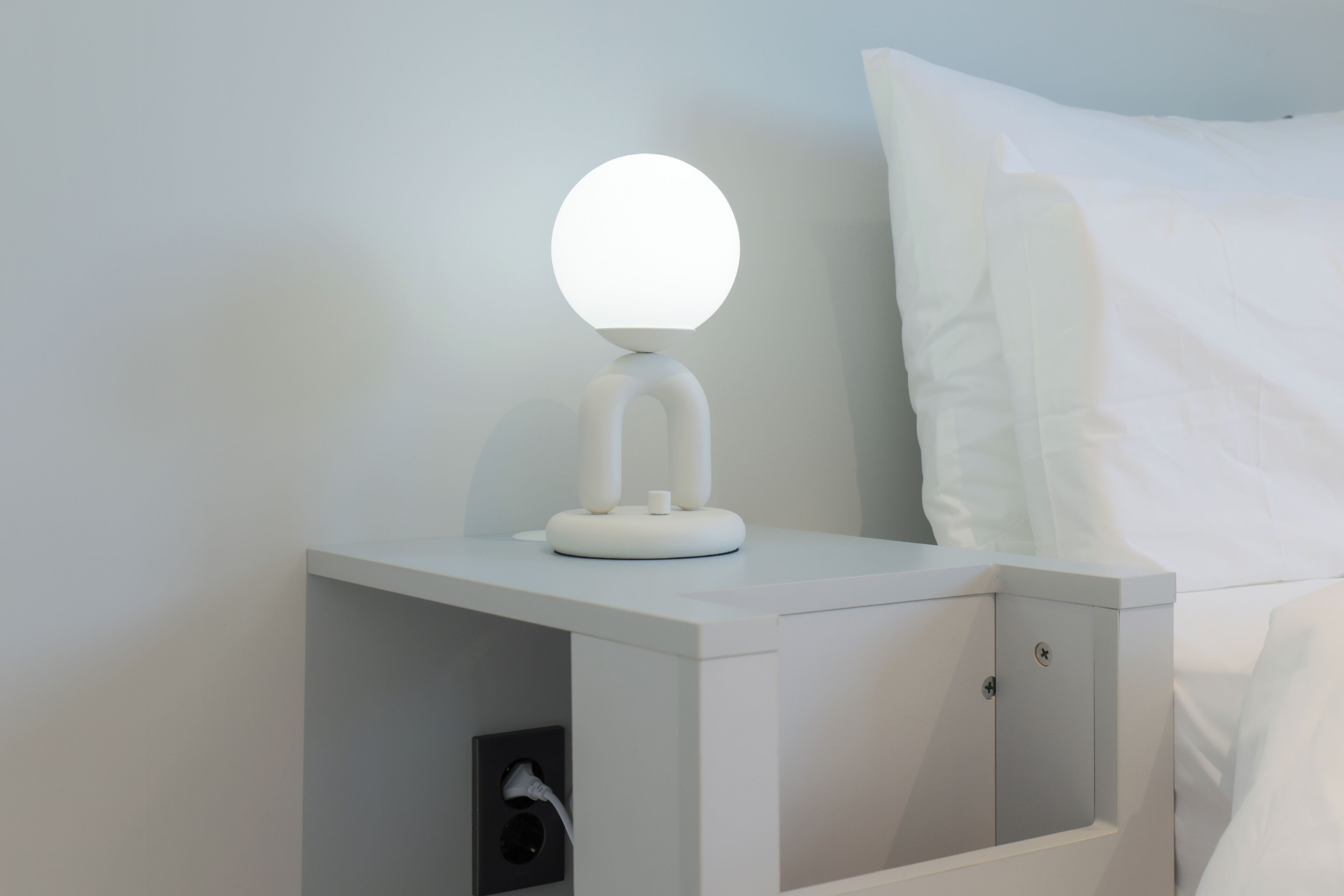A white bedside table with a round mirror and a charging port.