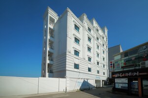 Un edificio de varios pisos con fachada blanca y numerosas ventanas.