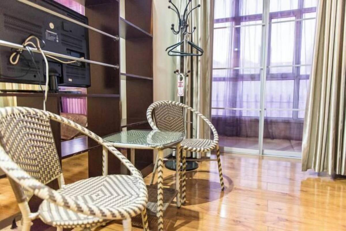 A room with a glass table and wicker chairs, a coat rack, and a television.