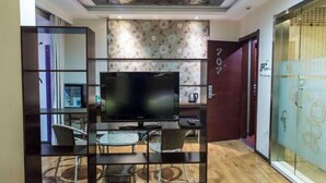 Habitació d'hotel amb televisió, una separació de vidre, un paviment de fusta i el número '707' a la paret.