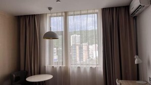 A hotel room with a large window, a round table, a chair, and an air conditioning unit. - HanTing Hotel (Rui'an Wansong Road) (Rui'an)