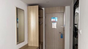 A hallway with a wooden wardrobe, a mirror, and a door with a sign. - HanTing Hotel (Rui'an Wansong Road) (Rui'an)