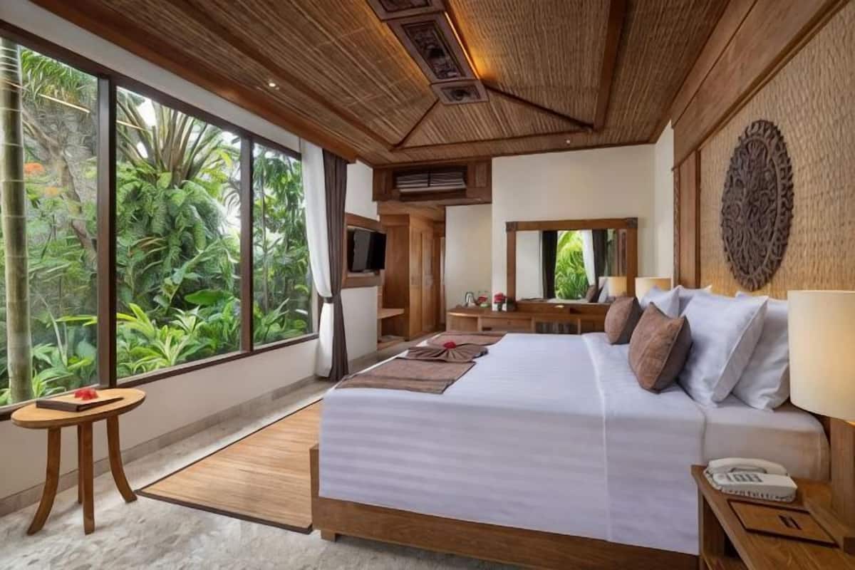 Una camera da letto con un letto grande, una televisione, uno specchio e vista sul verde.
