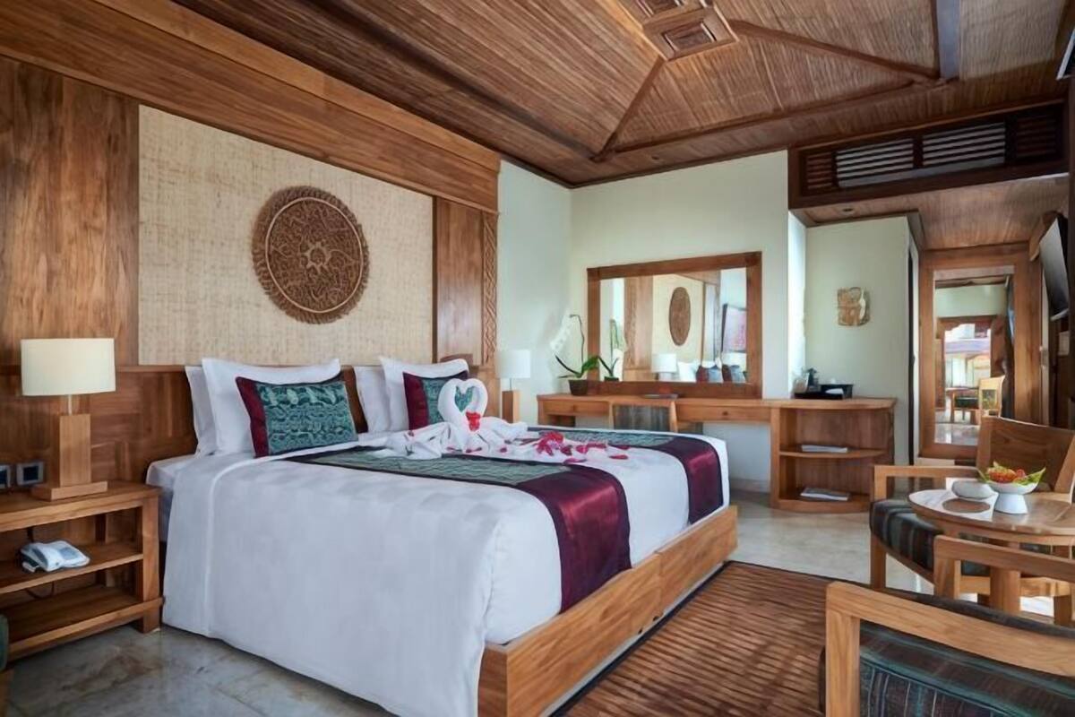 Camera da letto con un letto grande, una testiera in legno, comodini, una scrivania e una sedia.