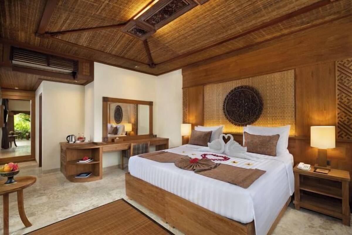 Un'ampia camera da letto con un letto grande, una testiera in legno, comodini e uno specchio.