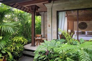 A covered outdoor area with a wooden pergola, a stone bench, and lush greenery. - Sakti Garden Resort & Spa (Ubud)