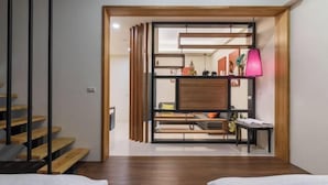 Ein modernes Interieur mit einer Holztreppe, einem Essbereich mit Tisch und Stühlen sowie einer pinkfarbenen Pendelleuchte.