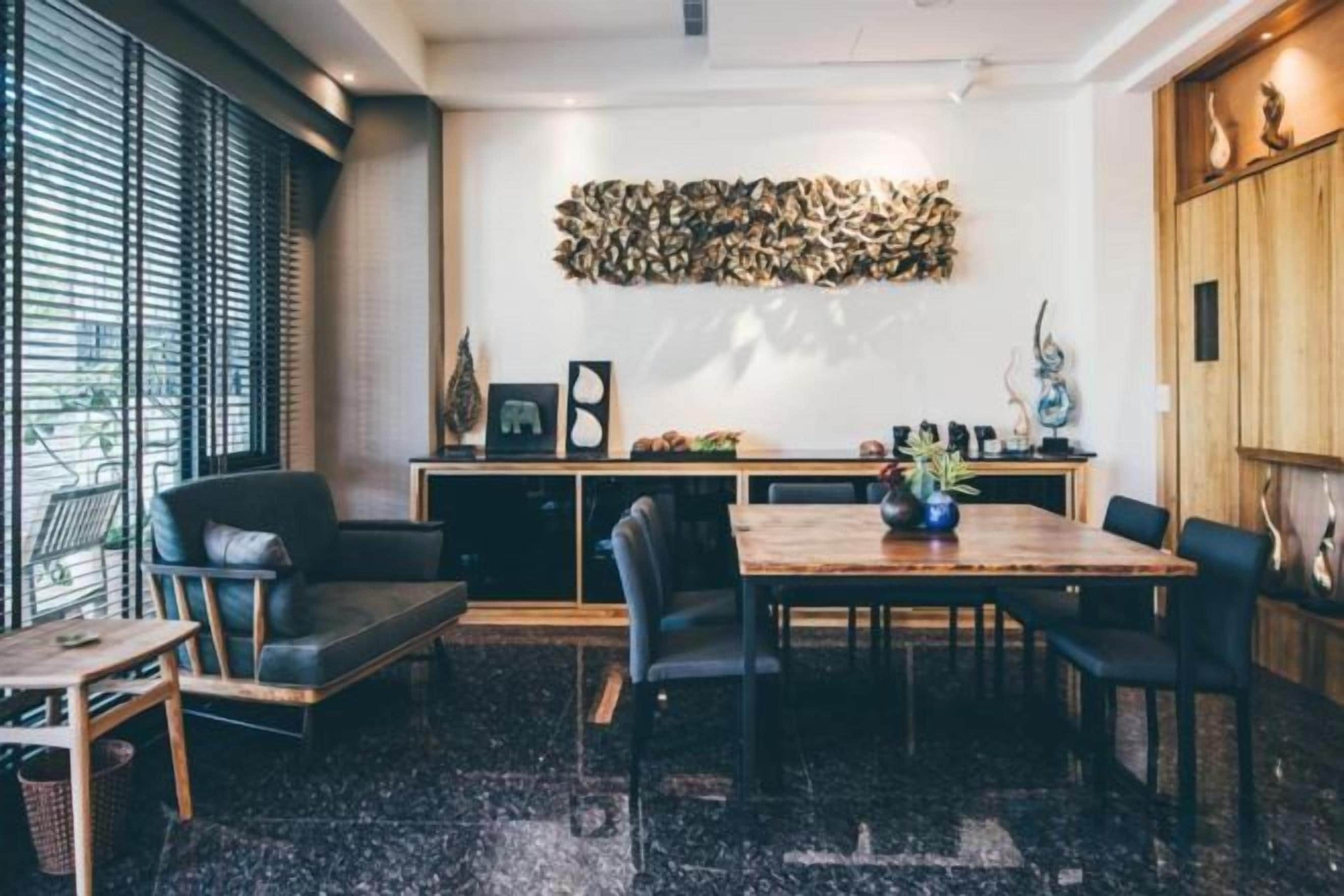 A dining area with a wooden table, black chairs, and a black and white patterned floor.