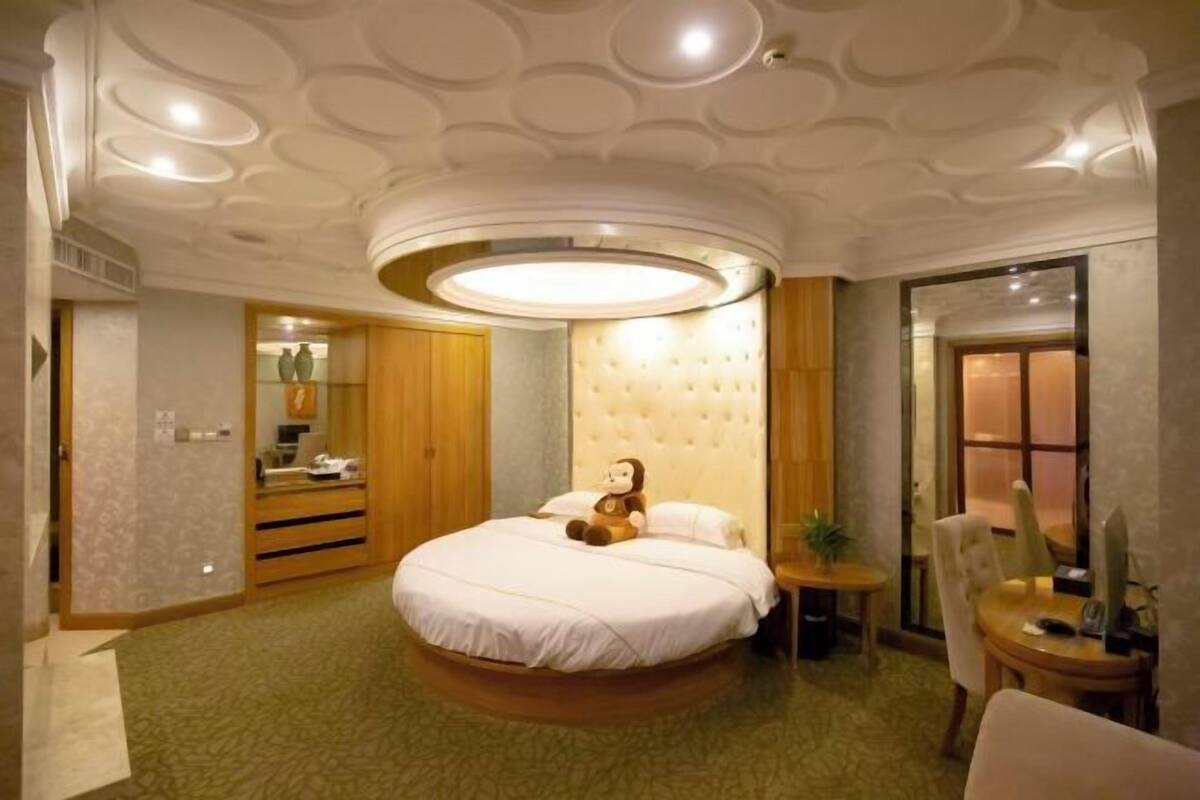 Ein Schlafzimmer mit einem runden Bett, einem gesteppten Kopfteil, einem Nachttisch und einem Sessel.